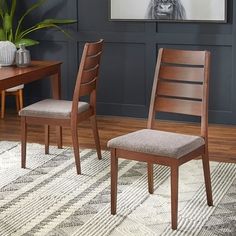 two wooden chairs sitting on top of a rug next to a table and chair set