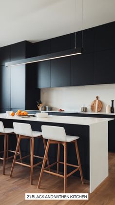 a kitchen with black cabinets and white stools in front of an island countertop