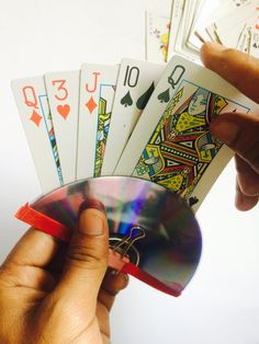 a hand holding several playing cards and a cd in it's left hand,