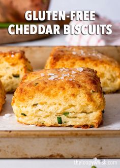 three cheddar biscuits sitting on top of a baking pan with the words gluten - free cheddar biscuits