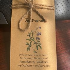 a piece of brown paper tied to a wooden table with a tag on it that says, please slow these seed in loving memory of jonathan r wellborn