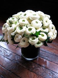 a vase filled with white flowers on top of a wooden table