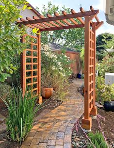 an outdoor garden with brick walkway and wooden trellis