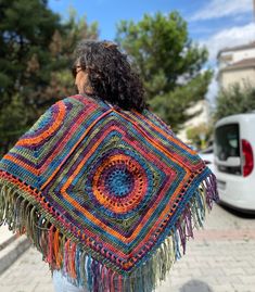 a woman wearing a crocheted shawl on the street