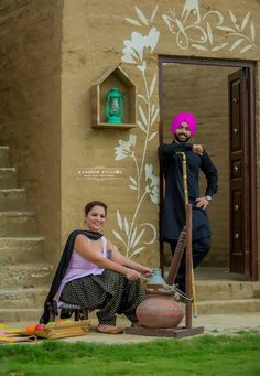 two people sitting on the ground in front of a building