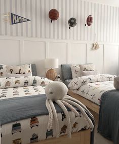 two beds in a room with blue and white striped walls, one has a stuffed animal on the bed