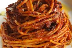 some spaghetti is piled on top of each other in a white bowl with sauce and seasoning