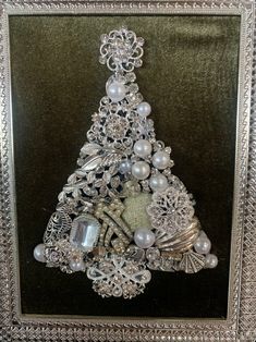 a christmas tree made out of pearls and other items in a silver frame on a black background