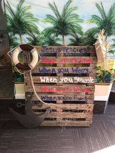 a pirate ship made out of wooden pallets with words written on the sides and palm trees in the background