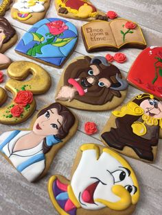 some decorated cookies on a table with disney princesses and beauty and the beast characters