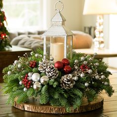 A holiday centerpiece of noble fir, white pine, incense cedar, silver glittery bead decorations, 2 red ball clusters, 2 silver ball clusters, 6 red berry clusters, 6 Australian pinecones with silver glitter, and an LED white lantern sitting on a wood round on a table. Dining Table Candle Decor, Christmas Tree Centerpieces For Table, Table Candle Decor, Christmas Lantern Centerpieces, Dining Table Candle, Art Floral Noel, Frosted Pinecones, Holiday Centerpieces Christmas, Red Ball Ornaments