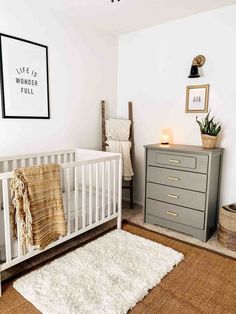 a baby's room with a white crib, dresser and rug on the floor