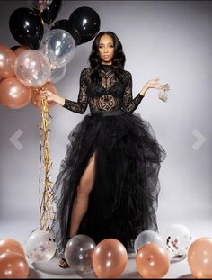 a woman in a black dress standing next to balloons