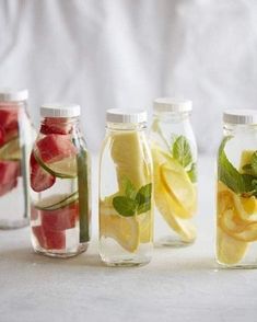 four glass jars filled with different types of fruit