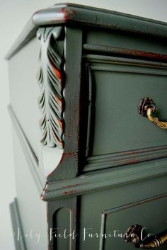 an old dresser painted in gray and gold with red paint on the top, has ornate handles