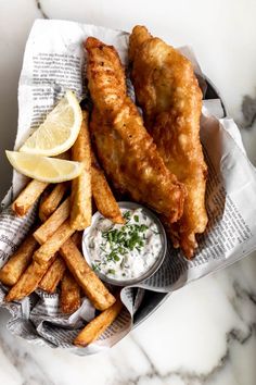 fried fish and fries are served with lemon wedges