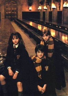 three young harry potters sitting on the floor in front of a building with their arms around each other