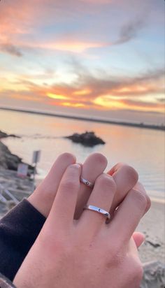 a person holding their hand up to the sky with sunset in the back ground behind them