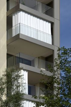 an apartment building with balconies and trees in front