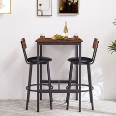 two stools and a table in a room with pictures on the wall behind them