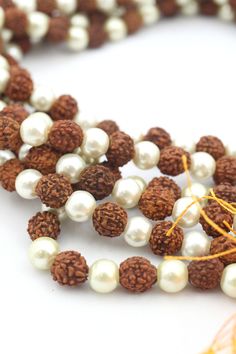 These beautiful beads are made from Rudraksha seeds paired with pearls. Hailing from India, Rudraksha seeds are traditionally used as prayer beads in Hinduism. They are the seeds of the Rudraksha tree, and legend has it that when Lord Shiva awoke from a long meditation, he shed a tear; from this tear grew the Rudraksha tree.Pearls are known as "moti" in Hindi, and they are symbolic of the moon. They encourage positive thinking and balance, and are believed to attract good luck and wealth. Bead S 8mm Pearl Beads Spiritual Necklace, Traditional Pearl Necklace With Gemstone Beads, Festival Pearl Necklace With Round Beads, Traditional White Mala With Gemstone Beads, Traditional Pearl Beads As A Gift, Traditional Pearl Beads For Gifts, White Round Beads Mala For Rituals, White Polished Beads Mala For Festivals, White Mala With 8mm Beads For Rituals