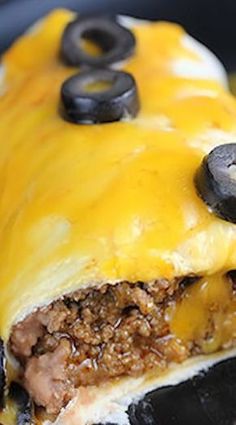 an enchilada covered in cheese and black olives