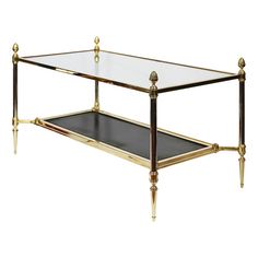 a glass and brass coffee table with two shelves on the bottom, one shelf is turned upside down