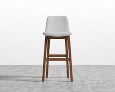 a white stool sitting on top of a cement floor next to a wooden bar stool