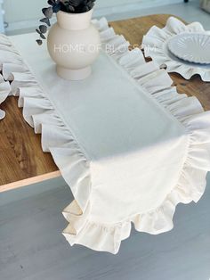 a white vase with flowers sitting on top of a table next to plates and napkins