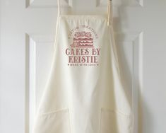 an apron hanging on a door with the words cakes by kristie printed on it