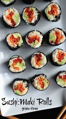 several sushi rolls on a white plate with chopsticks