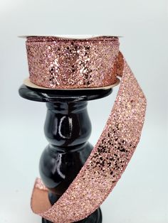 a pink glitter ribbon on top of a black stand