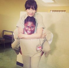 a woman in prison uniform is hugging another woman's head with her arms around her shoulders