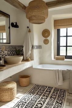 a white bathroom with black and white tiles on the floor, large mirror above the bathtub