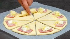 a person is making pizza with ham and cheese on the top crust, ready to be cut into small pieces