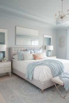 a white bed sitting in a bedroom next to a window covered in blue and pink pillows