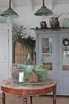 a table with some glass bottles on top of it and candles in front of it