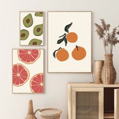 three oranges and an avocado are hanging on the wall