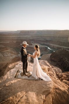 a bride and groom standing on the edge of a cliff at sunset in grand canyon national park