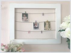 a white frame with pictures and clothes pins hanging from it's sides next to flowers