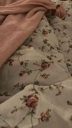 an unmade bed with pink sheets and flowers on it