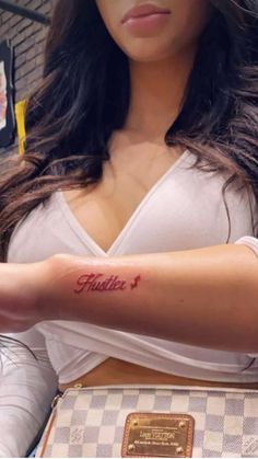 a woman with a tattoo on her arm holding onto a purse and looking at the camera