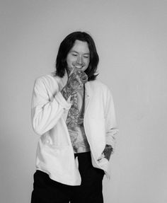 black and white photograph of a man with long hair wearing a jacket, tie and pants