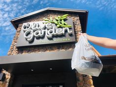 a person holding a bag in front of a building that says blue garden italian kitchen