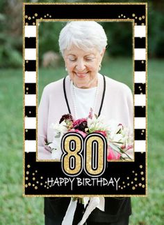 an older woman holding a birthday card with the number 80 on it and flowers in her hand