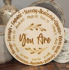 a wooden plaque with the words you are surrounded by other plates and bowls on a table