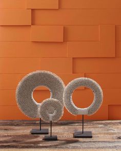 two sculptures on stands in front of an orange wall