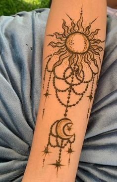 a woman's arm with a sun and moon tattoo on the side of her arm