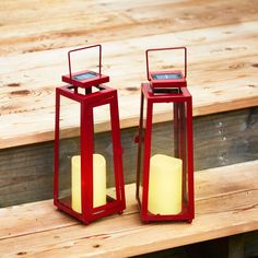 two small red lanterns sitting on top of a wooden table next to each other with candles in them