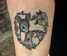 a tattoo on the arm of a person with a deer and flowers around it's neck